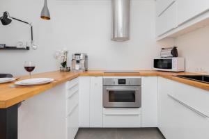 a kitchen with white cabinets and a wooden counter top at Spacious Apartment Aleja Rzeczypospolitej with Balcony by Noclegi Renters in Gdańsk