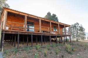 duży drewniany dom na słupach na polu w obiekcie Fireside Cabin w mieście Underberg