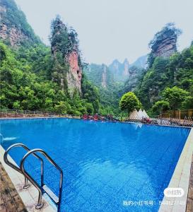 a large swimming pool with mountains in the background at Zhumaxi Leisure Lodge in Zhangjiajie