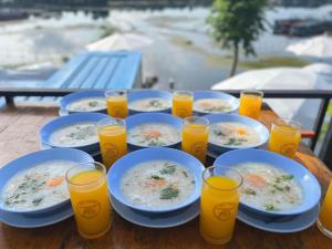 a table with plates of food and glasses of orange juice at ปลายเขื่อนแคมป์ปิ้ง in Sirindhorn