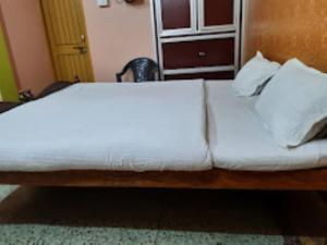 a bed with white sheets and pillows in a room at Hotel santi vihar,Jehanabad in Jahānābād