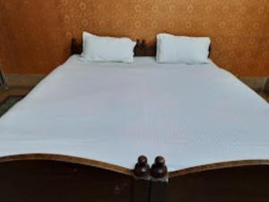 a bed with white sheets and two pillows on it at Hotel santi vihar,Jehanabad in Jahānābād