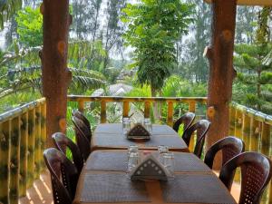 a table and chairs on a porch with trees at Sundarban Tiger Roar Resort in Purbbadulki