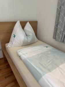 a bed with white sheets and pillows on it at Ferienwohnung am Bauernhof Familie Alt in Rinn