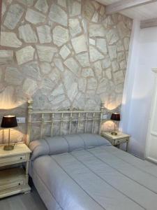 a bedroom with a stone wall with a bed and two tables at Las Tres A in Segura de la Sierra