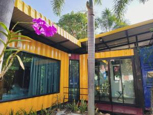 a yellow building with a purple flower on it at Beach Box at Pran in Sam Roi Yot