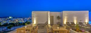 a restaurant with tables and chairs on a balcony at night at Hotel Papadakis in Naousa