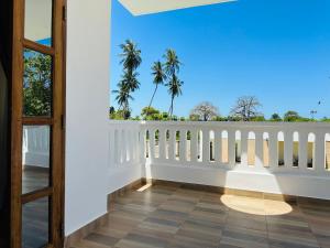 a balcony with a white fence and palm trees at Almond Ridge - Villa Mfalme in Kinondo