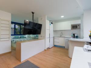 Una cocina con gabinetes blancos y un televisor de pantalla plana. en Suites Garden DALI 14, en Las Palmas de Gran Canaria