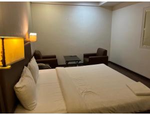 una camera d'albergo con un letto e due sedie di Hotel City Inn, Kakinada, Andhra Pradesh a Kākināda