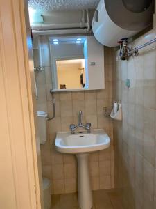 y baño con lavabo, espejo y aseo. en Διαμέρισμα στο κέντρο της πόλης, en Chios