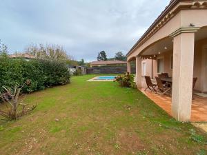 une arrière-cour d'une maison avec une piscine et une table dans l'établissement Villa spacieuse avec piscine privé , Vallée du Lot, à Prayssac