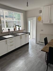 ロンドンにあるBalham, South London Spacious Guest House F2, 6 rooms availableの白いキャビネットと木製の床を備えたキッチン