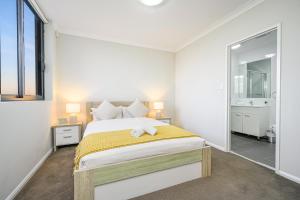 a white bedroom with a bed and a bathroom at Parramatta lovely 2br near station with City view in Sydney
