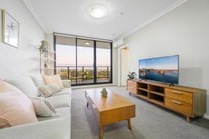 ein Wohnzimmer mit einem Sofa und einem TV in der Unterkunft Parramatta lovely 2br near station with City view in Sydney