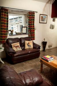 Una sala de estar con un sofá de cuero marrón y una mesa. en RB Contractor Stays - Onnen, en Pwllheli