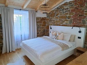 a bedroom with a large white bed with a brick wall at Apartament VILLA SABAVIA in Gračišče
