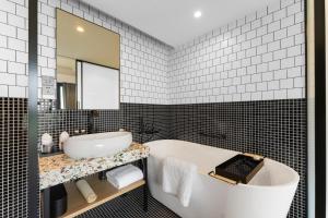 uma casa de banho com uma banheira, um lavatório e um espelho. em Mia Hotel - Shanghai Xuhui Jiaotong University em Xangai