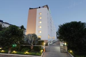 a white building with a palm tree in front of it at Lemon Tree Hotel Chandigarh in Chandīgarh