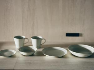 four bowls and cups sitting on a wooden table at illi Com Shimokitazawa in Tokyo