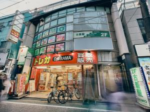 a building with two bikes parked in front of it at illi Com Shimokitazawa in Tokyo