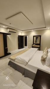 una grande camera da letto con un grande letto con lenzuola bianche di برج رفيف a Baish