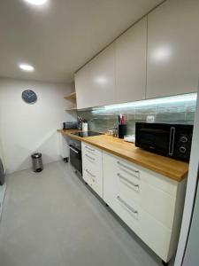 a kitchen with white cabinets and a black microwave at Casa da Corredoura in Évora