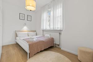 ein Schlafzimmer mit einem Bett, einem Fenster und einem Stuhl in der Unterkunft ma suite - modern apartment 2P central Augsburg in Augsburg