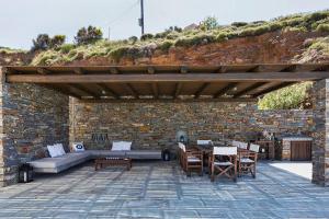 patio z kamienną ścianą i drewnianą pergolą w obiekcie Villa Faros Vourkari Kea with private pool and stunning views w mieście Vourkari