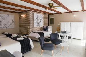 a bedroom with two beds and a table and chairs at Greenfields Guesthouse & Restaurant in Alberton