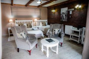 a bedroom with a bed and two chairs and a table at Greenfields Guesthouse & Restaurant in Alberton