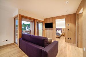 a living room with a purple couch and a tv at Huetterhof Apartement Winter in Caines