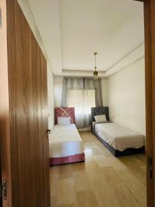 1 dormitorio con 2 camas y puerta abierta en Cosy appartement, en Nouaceur