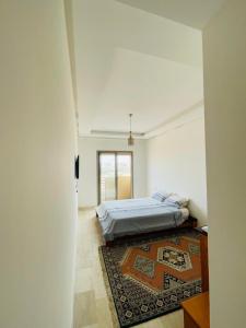 Habitación blanca con cama y alfombra en Cosy appartement, en Nouaceur
