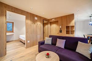 a living room with a purple couch and a bed at Huetterhof Apartement Winter in Caines