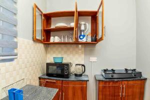 a kitchen with a stove and a microwave at Cozy & Stylish 1-Bedroom Apartment by Havana Properties located in Kinondoni Vijana in Dar es Salaam