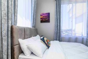 a bedroom with a bed with white pillows and a window at Cozy & Stylish 1-Bedroom Apartment by Havana Properties located in Kinondoni Vijana in Dar es Salaam