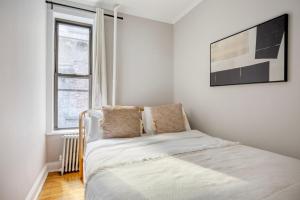 a white bedroom with a bed and a window at West Village 1br w wd nr park NYC-1275 in New York