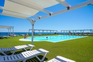 a swimming pool with chairs and a pier in the background at Hotel Capo Campolato in Brucoli