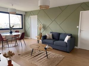 a living room with a blue couch and a table at L'Échappée Belle - Appartement charmant et chaleureux in La Séguinière