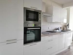 a kitchen with white cabinets and a microwave at Le Cocon des Dunes in Quend