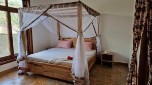 a bedroom with a canopy bed with pink pillows at Bantu Home in Paje