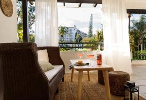 - un salon avec une chaise et une table avec des verres à vin dans l'établissement Charming and spacious apartment in Medina Garden - Puerto Banús, à Marbella