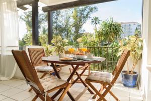 - une table en bois et 2 chaises sur un balcon avec boissons dans l'établissement Charming and spacious apartment in Medina Garden - Puerto Banús, à Marbella