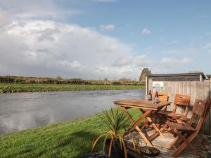 a table and chairs sitting on a deck next to a river at Athelney Cottage in Bridgwater