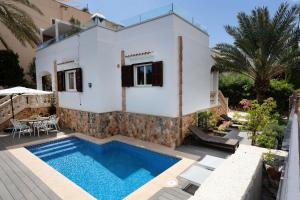 a villa with a swimming pool in front of a house at La casa Escaniana in Cala Santanyi