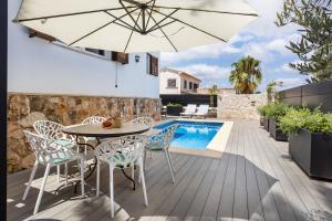 a patio with a table and chairs and an umbrella at La casa Escaniana in Cala Santanyi