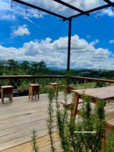 a wooden deck with picnic tables and a view of the forest at Halcyon Homestay Mang Den in Kon Von Kla