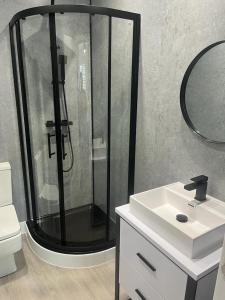 uma casa de banho com um chuveiro e um lavatório branco em The Boyd - Coorie Doon em Prestwick