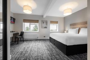 Habitación de hotel con cama grande y escritorio. en The Stones Hotel en Salisbury